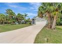 Beautiful single-story home with a long driveway, tropical palm trees, and an attached two-car garage at 4322 Concert St, Port Charlotte, FL 33948