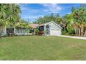 Inviting single-story home with a well-manicured lawn, mature trees, and an attached two-car garage at 4322 Concert St, Port Charlotte, FL 33948