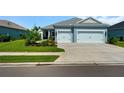 Charming blue home featuring a well-maintained lawn and a two-car garage with a concrete driveway at 4407 Big Woods Way, Parrish, FL 34219