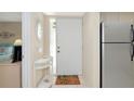 Bright condo foyer with tile flooring, white decor, a welcome mat, and an adjacent stainless steel refrigerator at 4650 Ringwood Meadow # 37, Sarasota, FL 34235