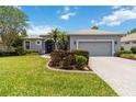 Charming one-story home featuring a well-manicured lawn, beautiful landscaping, and an attached two-car garage at 664 Planters Manor Way, Bradenton, FL 34212