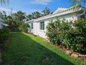 Well-maintained side yard with lush green grass, flowering bushes, and tropical landscaping against the white exterior at 730 Spanish S Dr # 99, Longboat Key, FL 34228