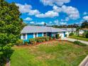 Bright blue single-story house with white trim, manicured lawn, and lush landscaping on a sunny day at 1312 73Rd Nw St, Bradenton, FL 34209