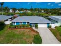Beautiful single-story home with a blue exterior, metal roof, and lush landscaping near the lake at 1312 73Rd Nw St, Bradenton, FL 34209