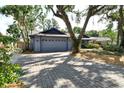 Paver driveway leading to a two-car garage, surrounded by mature trees and landscaping for added curb appeal at 4137 Woodview Dr, Sarasota, FL 34232