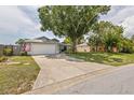 View of a single-story home featuring an attached two-car garage, front yard with mature trees, and partial lawn at 4222 Lanai Dr, Sarasota, FL 34241