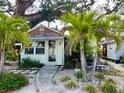 Quaint cottage with palm trees, stone walkway, and a cozy, inviting front yard at 4412 125Th W St, Cortez, FL 34215