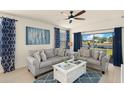 Cozy living room with plush gray seating, blue accent rug, and a view of the serene pond outside at 5358 Shell Mound Cir, Punta Gorda, FL 33982
