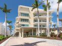 Stunning exterior of the elevated beachfront building with palm trees and tropical landscaping at 6512 Midnight Pass Rd # 301, Sarasota, FL 34242