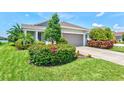 Charming home featuring a well-manicured lawn, colorful flower beds, and lush greenery around the entrance at 13849 Old Creek Ct, Parrish, FL 34219