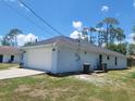 Side exterior of home with a two-car garage and well-maintained lawn at 1422 Jakway Rd, North Port, FL 34288