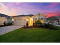 Charming one-story home showcasing a landscaped front yard and brick driveway under a picturesque sky at dusk at 18317 Gulf Ranch Pl, Bradenton, FL 34211