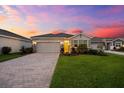 Charming one-story home showcasing a landscaped front yard and brick driveway under a picturesque sky at sunset at 18317 Gulf Ranch Pl, Bradenton, FL 34211