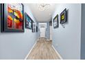 Bright hallway featuring light wood floors, gallery wall, and decorative lighting, leading to the front door at 18317 Gulf Ranch Pl, Bradenton, FL 34211