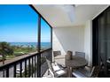 Balcony with table and chairs overlooking a view of palm trees and the ocean at 2045 Gulf Of Mexico Dr # M1-505, Longboat Key, FL 34228