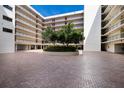 Beautiful courtyard with lush trees, colorful flowers, and brick-paved driveway at this modern condo complex at 2045 Gulf Of Mexico Dr # M1-505, Longboat Key, FL 34228