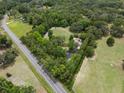 Aerial view highlighting the home and its expansive, tree-filled surroundings at 22063 Lake Lindsey Rd, Brooksville, FL 34601