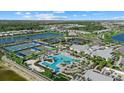 Aerial view of a resort-style community pool, tennis courts, and lush landscaping with a lake backdrop at 26000 Seastone Dr, Englewood, FL 34223