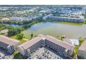 Scenic aerial view of a condo complex with beautiful lake, lush greenery, community tennis court, and swimming pool at 3521 Lake Bayshore Dr # 3521, Bradenton, FL 34205
