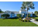 Community clubhouse featuring a blue and white exterior, manicured lawn, and tropical landscaping at 3631 Shimmering Oaks Dr, Parrish, FL 34219