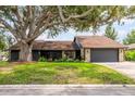 A beautiful single-story home with a stone facade and two-car garage sits under a large shade tree at 4612 Masefield Pl, Sarasota, FL 34241