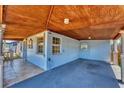View of the covered carport with wood paneled ceiling, textured blue exterior, and tile flooring at 513 25Th W Ave, Bradenton, FL 34205