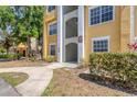 Close-up shot of the yellow condo entrance showcasing well-maintained walkways and lush greenery at 5552 Bentgrass Dr # 7-301, Sarasota, FL 34235