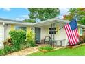 A cozy front porch features an American flag, yellow shutters, a chair, and a brick pathway at 5603 1St Avenue Dr Nw, Bradenton, FL 34209
