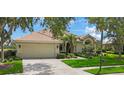 Well-maintained home with lush lawn, mature trees and bushes, and a paved driveway leading to an attached garage at 9635 Discovery Ter, Bradenton, FL 34212