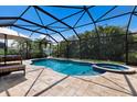 A stunning screened-in pool area with a luxurious in-ground pool, attached spa, and lush tropical landscaping at 11411 Spring Gate Trl, Bradenton, FL 34211