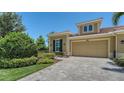 Charming home featuring a tile roof, two-car garage, brick paver driveway and lush green landscaping at 11603 Bluebird Pl, Lakewood Ranch, FL 34211