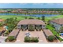 Aerial view of a condo building with multiple units, golf course, lake and parking under a sunny sky at 13711 Messina Loop # 102, Lakewood Ranch, FL 34211
