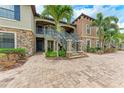 Close up exterior showcasing stone accents, palm trees, and stairways to multiple units and paved walkway at 13711 Messina Loop # 102, Lakewood Ranch, FL 34211