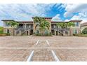 Attractive condo building exterior showcasing stone accents, palm trees, ample parking and stairways to multiple units at 13711 Messina Loop # 102, Lakewood Ranch, FL 34211