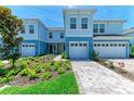 Beautiful blue townhome with a two-car garage and lush landscaping in the front yard at 305 Via Tuscany Ave, Sarasota, FL 34243