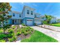 Beautiful blue townhome with a two-car garage and lush landscaping in the front yard at 305 Via Tuscany Ave, Sarasota, FL 34243