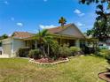 Low angle of the home showing a manicured lawn with beautiful landscaping with pink flamingos and a covered front porch at 3828 6Th W Ave, Palmetto, FL 34221
