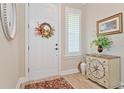 Welcoming foyer featuring a white door with a floral wreath, plantation shutters and stylish decor at 42250 Ramble Rd, Punta Gorda, FL 33982