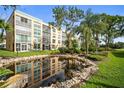 Exterior view of the building reflected in a rock-lined pond with lush green grass and landscaping at 4530 Pinebrook Cir # 109, Bradenton, FL 34209