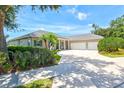Inviting single-story home with a three-car garage, palm trees, shutters, and a concrete driveway at 5373 Anthony Ln, Sarasota, FL 34233