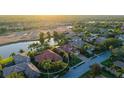 An aerial view showcases a single-story home with a tile roof near a golf course and a serene lake at 6914 Dominion Ln, Lakewood Ranch, FL 34202
