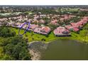Aerial view of a villa community with a pond, red tile roofs, mature trees, and manicured green lawns at 7331 Villa D Este Dr, Sarasota, FL 34238
