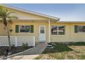 Inviting front porch with a charming yellow exterior, green shutters, and a well-kept garden area at 1190 Jamaica Rd, Venice, FL 34293