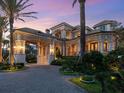 Luxurious home entrance with stone accents, a porte-cochere, and manicured gardens, illuminated by landscape lighting at 1423 & 1435 Hillview Dr, Sarasota, FL 34239
