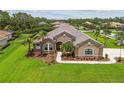 A meticulously landscaped yard surrounds this single-story home, complete with a sidewalk and palm trees at 16246 26Th E St, Parrish, FL 34219