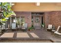 Covered front porch with chairs, planters, brick flooring and a beautiful wooden front door at 1671 South Dr, Sarasota, FL 34239