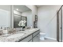 Well-lit bathroom features double sinks, granite countertops, and a modern glass-enclosed shower at 18106 Cropside Trl, Lakewood Ranch, FL 34211