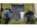 Aerial shot of a house with a screened-in pool, dark roof, and well-maintained surrounding landscape at 21498 Beaverton Ave, Port Charlotte, FL 33952