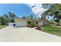 A single-story home features an attached garage, a spacious driveway, and manicured landscaping at 3707 Kingswood Dr, Sarasota, FL 34232
