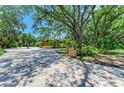 A paver driveway leads to a home surrounded by mature trees and lush landscaping at 4647 Stone Ridge Trl, Sarasota, FL 34232